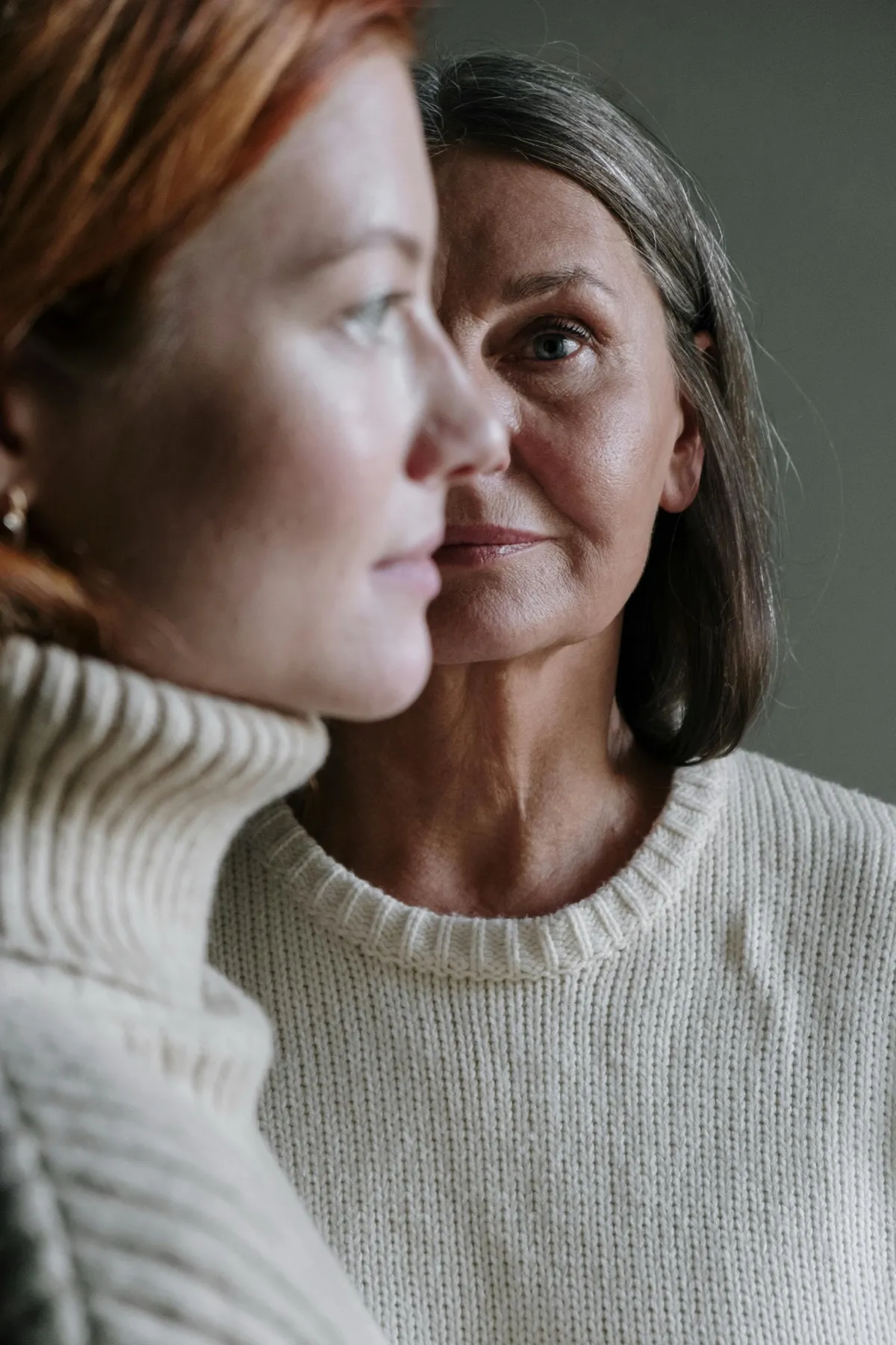 Two women standing close together, one resting against the other's shoulder